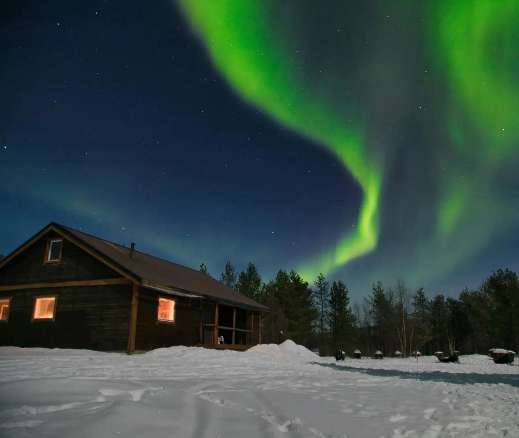 Northern lights over a cabin in the snow outside Kiruna